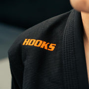 Black martial arts gi with 'HOOKS' logo on a blurred background