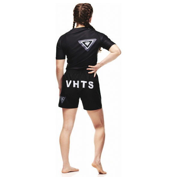 VHTS Rashguard Black Label: Athlete in black, white logo, standing, white background.