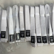 Hooks Origin White BJJ Belt, multiple folded belts laid out showing black label detail with logo patch visible.