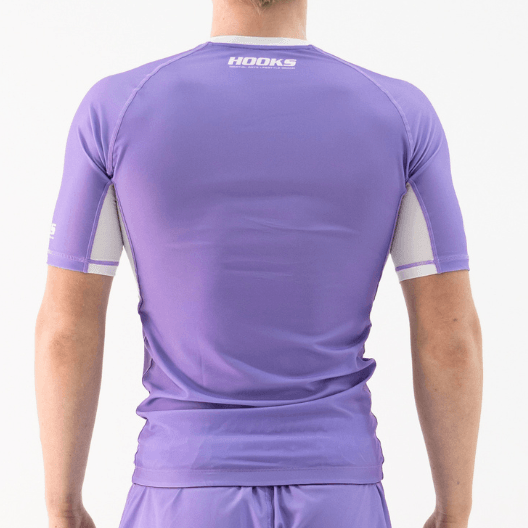 Hooks lavender short sleeve rash guard, back view worn, with white side panels and Hooks logo at collar.