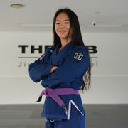 Hooks BJJ GI Prolight II Navy, worn front view with purple belt, arms crossed, showing shoulder patch detail
