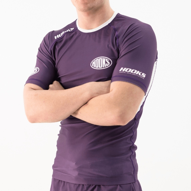 Hooks Fusion Short Sleeve Rash Guard in Plum, front angled view worn, showing chest and sleeve branding with white trim