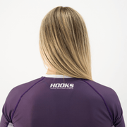 Hooks Women's Fusion Short Sleeve Rash Guard in Plum, back view worn, showing Hooks logo printed below the collar.