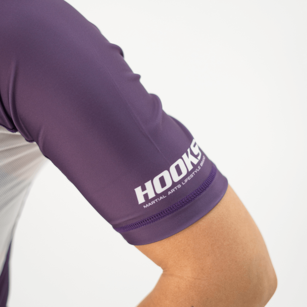 Hooks Women's Fusion Short Sleeve Rash Guard in Plum, close-up of sleeve cuff showing Hooks wordmark and overlock stitching