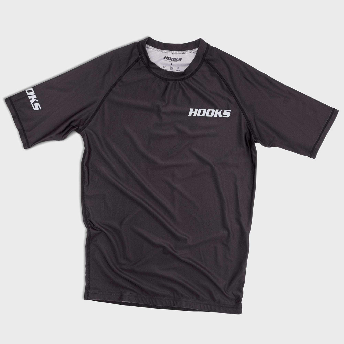 Hooks Core BJJ Rashguard Black Short Sleeve, front flat lay showing chest logo and sleeve branding