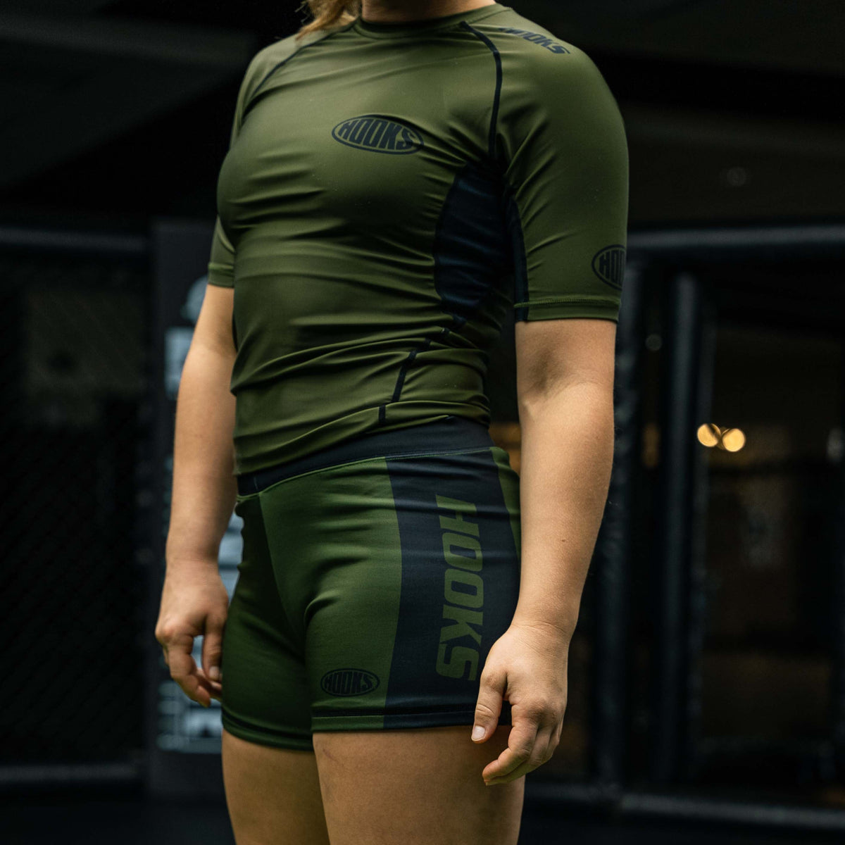 Hooks olive and black short sleeve rashguard and matching shorts, worn, side view showing panel detailing and logo placement