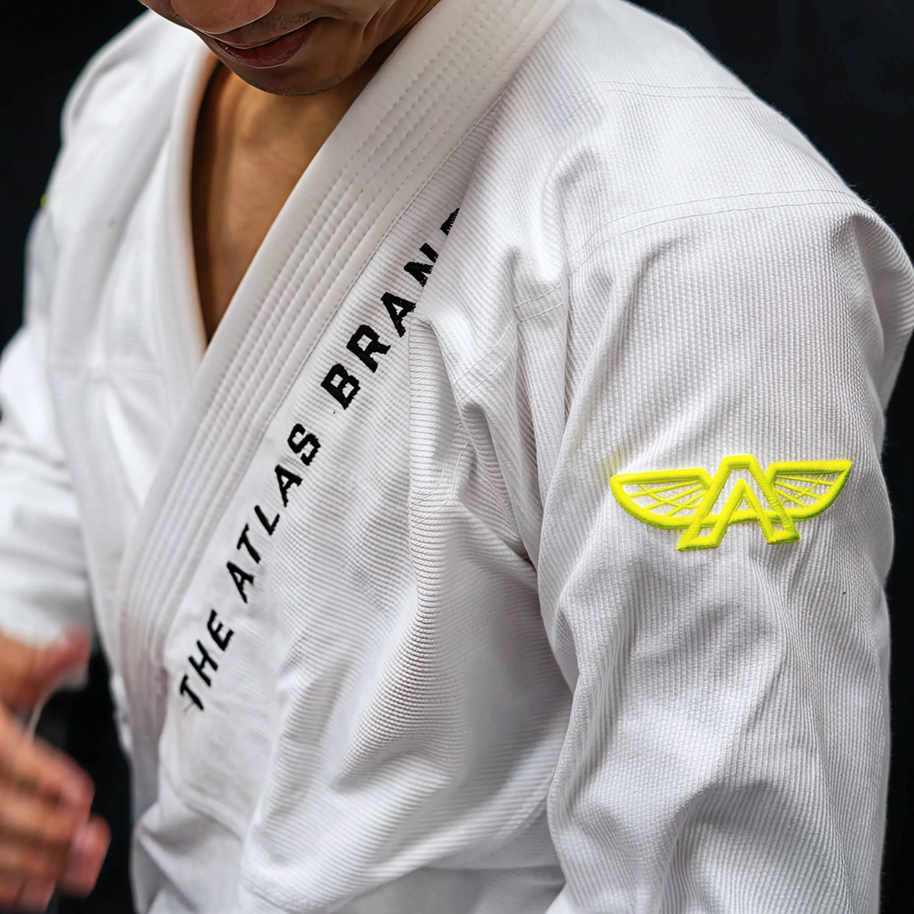 Front view of The Atlas Brand ICON White rashguard worn, showing embroidered logo detail.